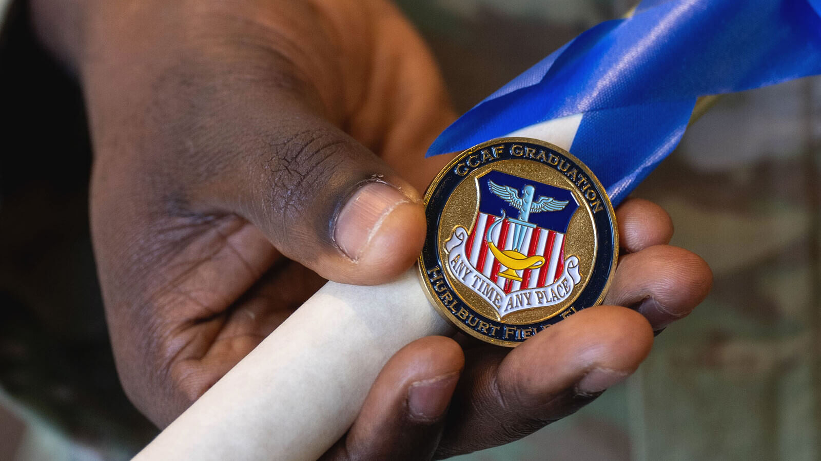 a hand holds a graduation pin