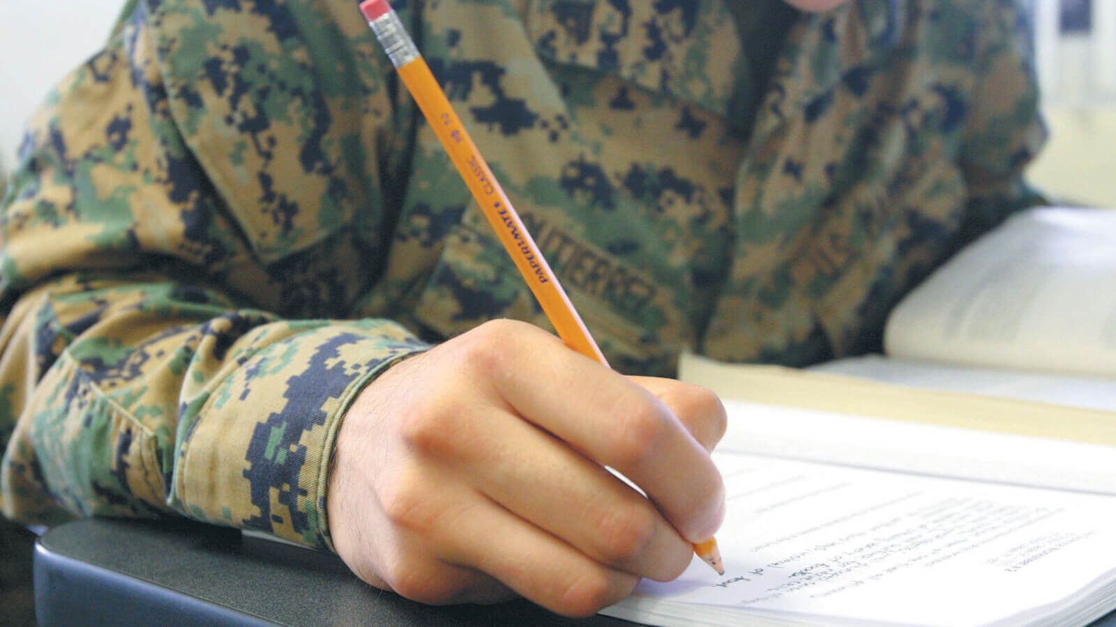 a student in military uniform works on class work