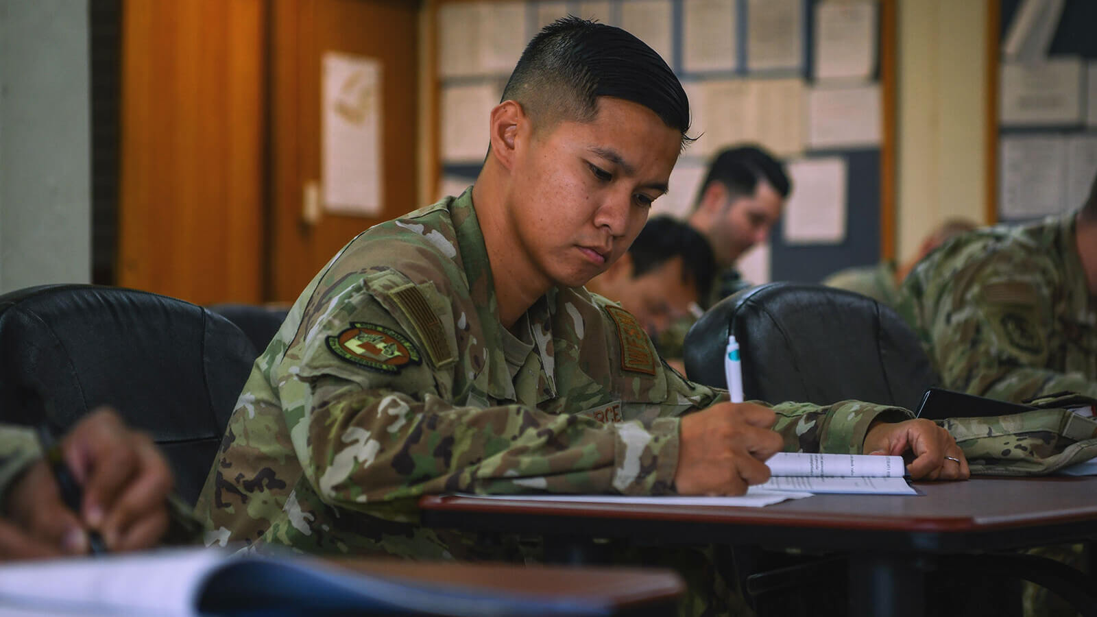 a military student dressed in his uniform does course work