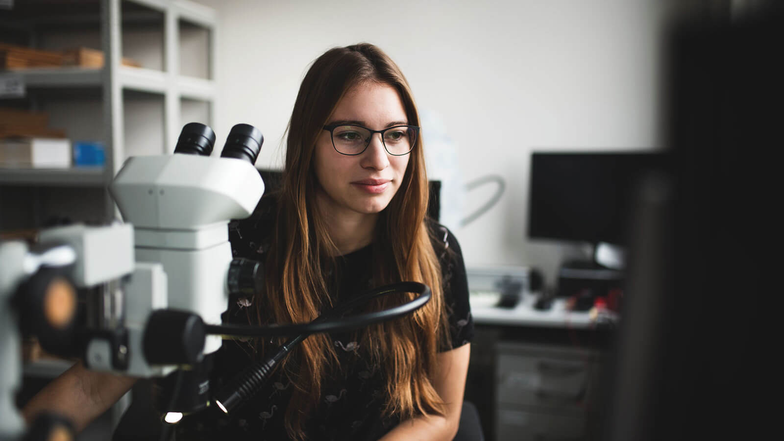 a student wearing glasses works in a lab at her high school