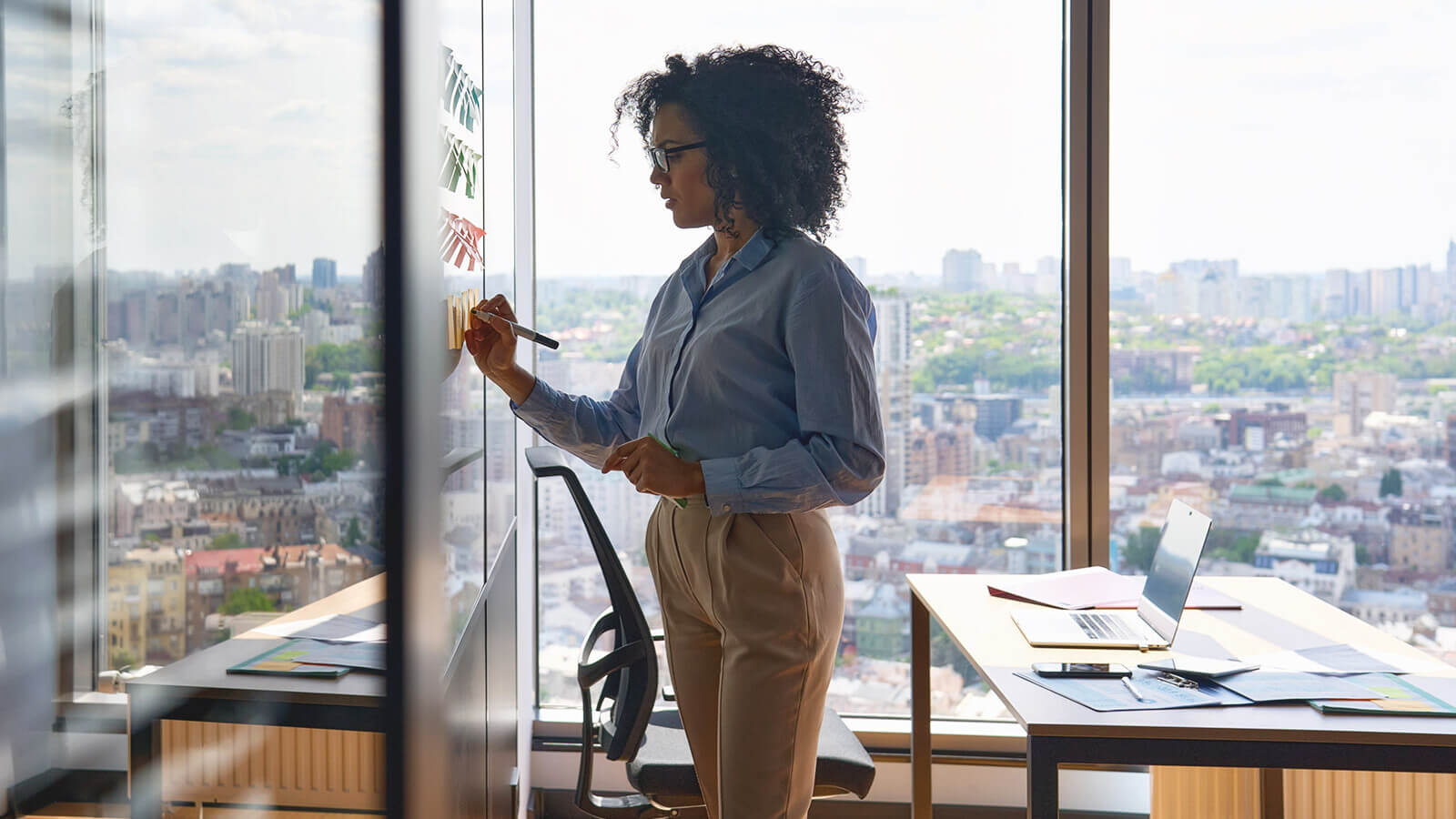 a woman stands at a dry erase board making notes for a meeting