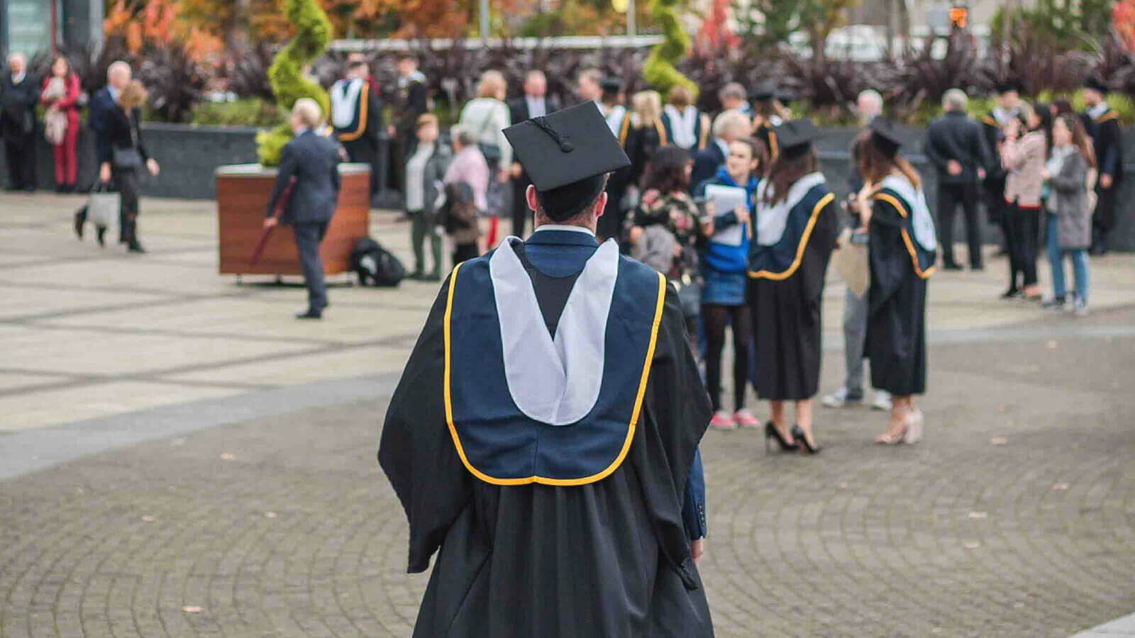 A student walks in a cap and gown at a graduation ceremony
