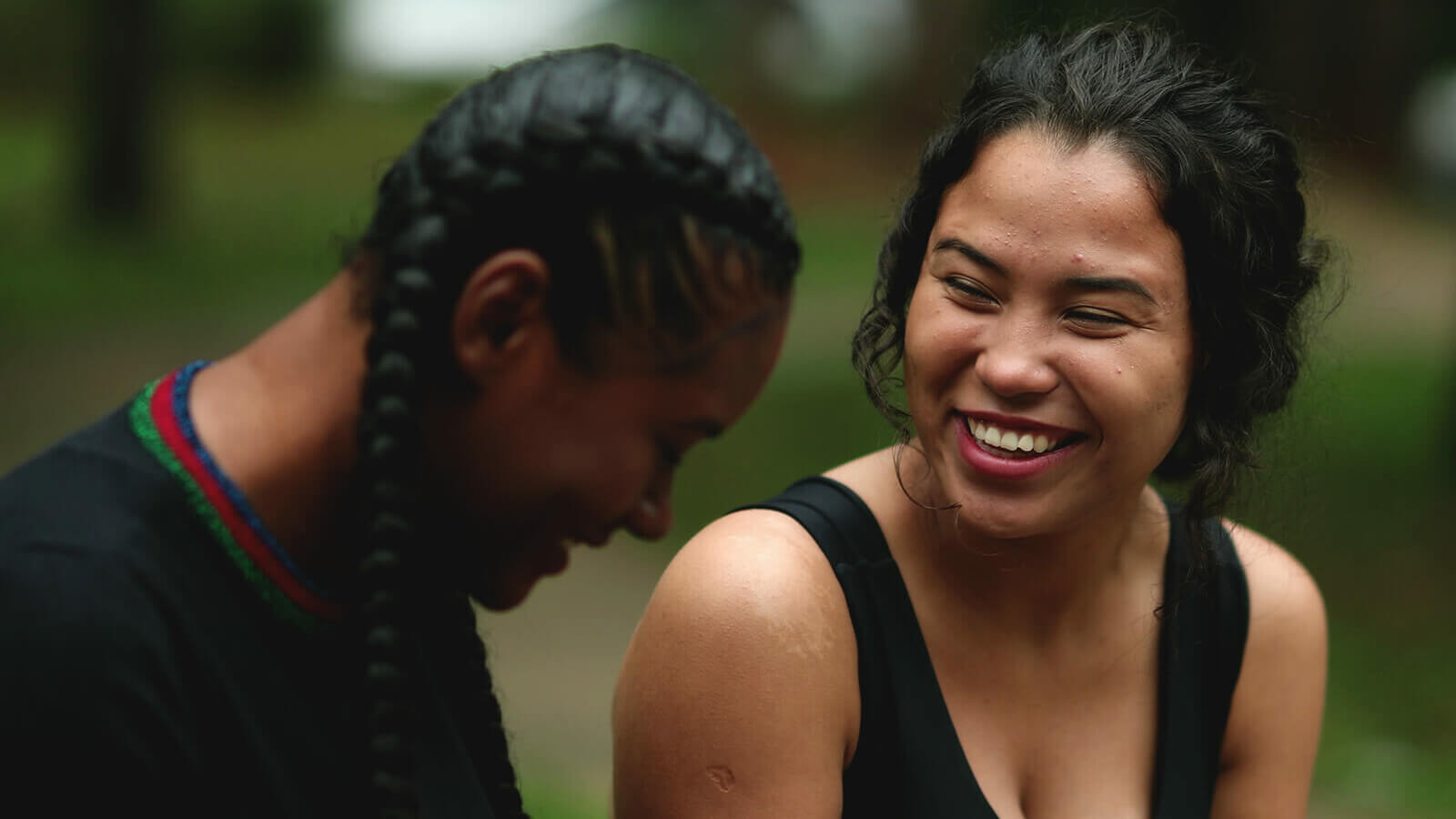 two young women talk and laugh while sitting outside