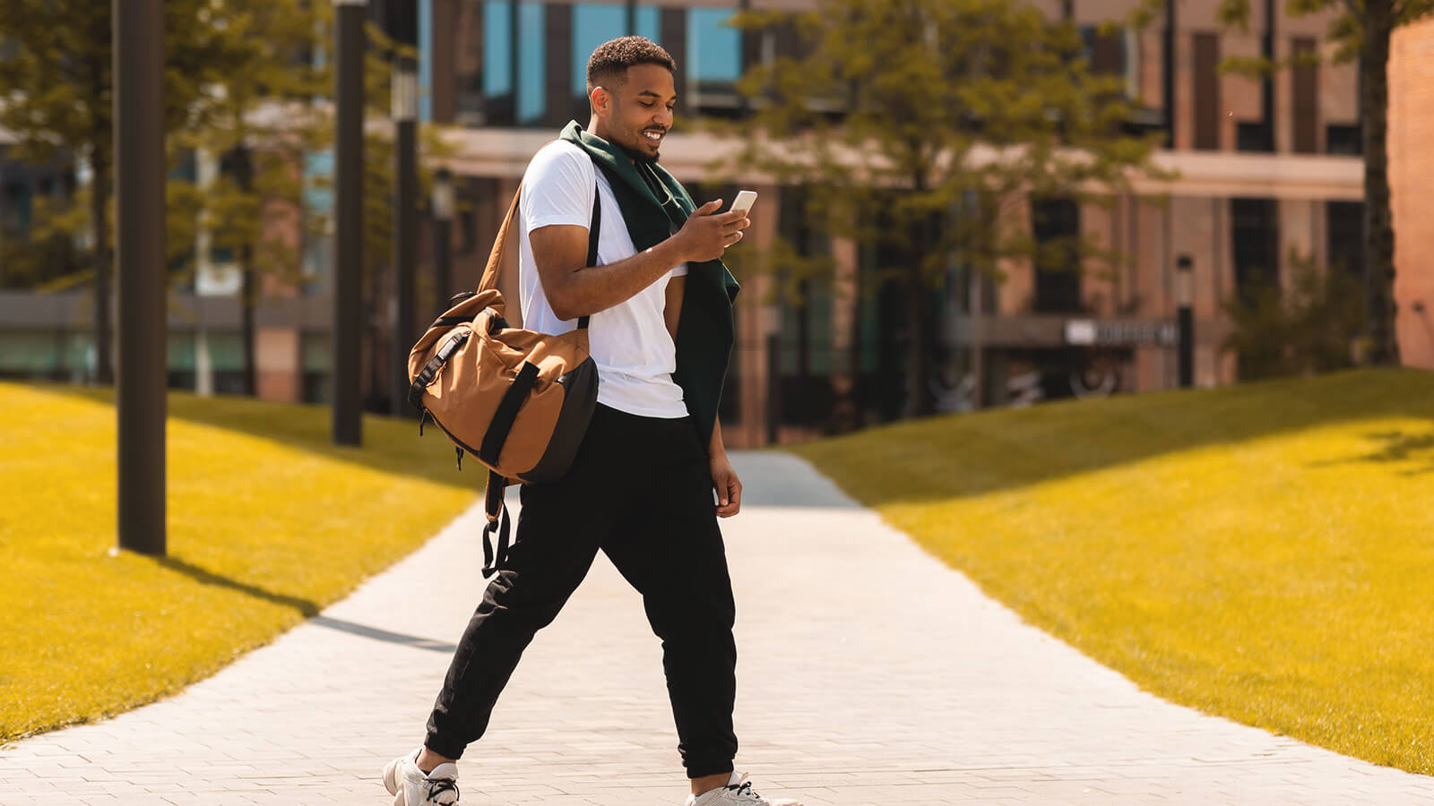 a student walks across campus looking at LinkedIn on a mobile device