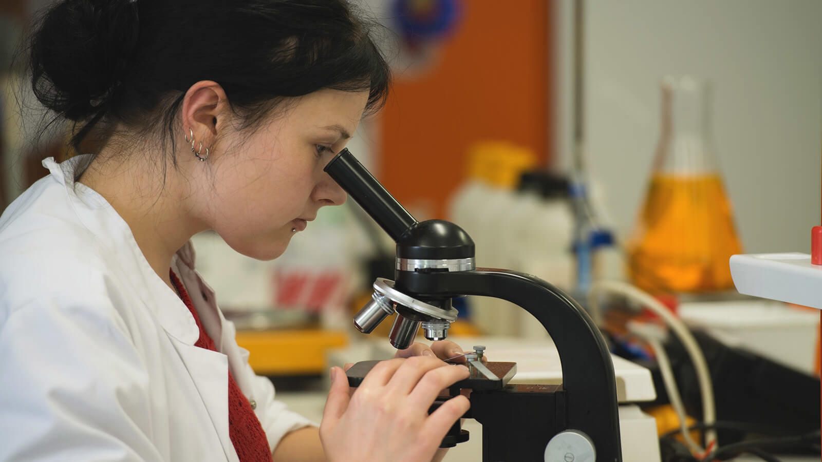 a student uses a microscope in her biology class