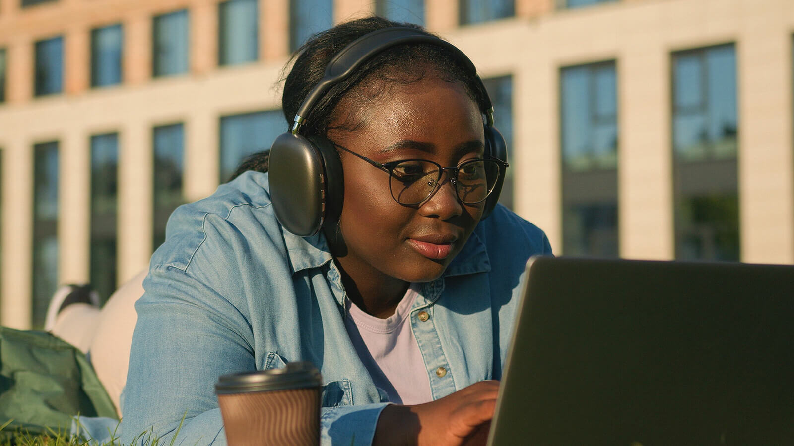 a student writes a letter on her laptop wearing ear phones