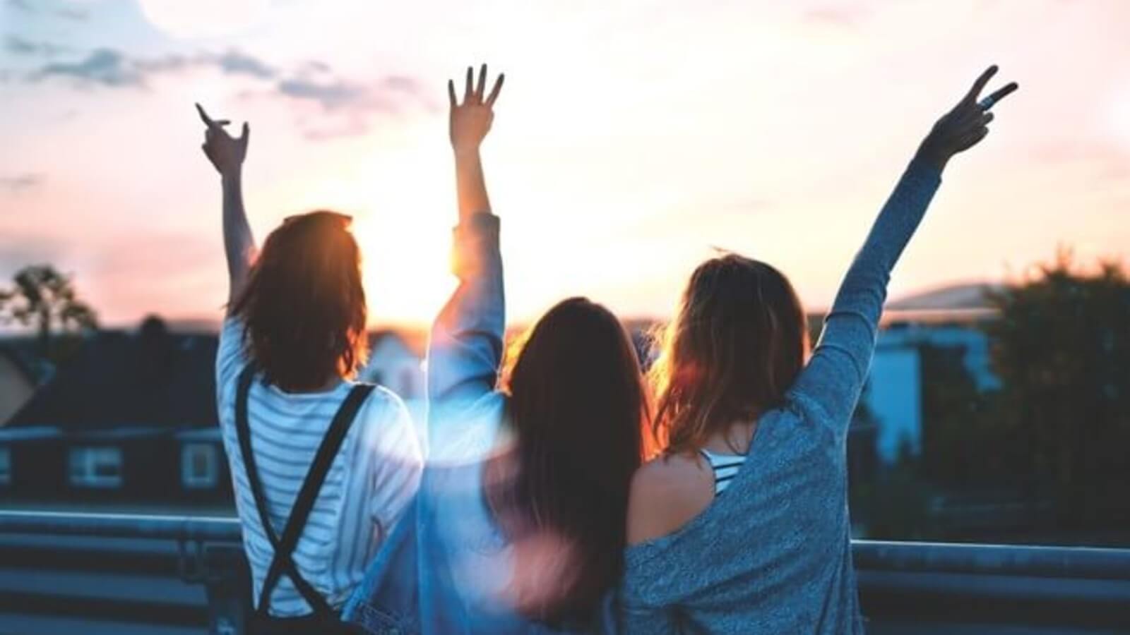 a group of college students with their arms in the air, shown from behind