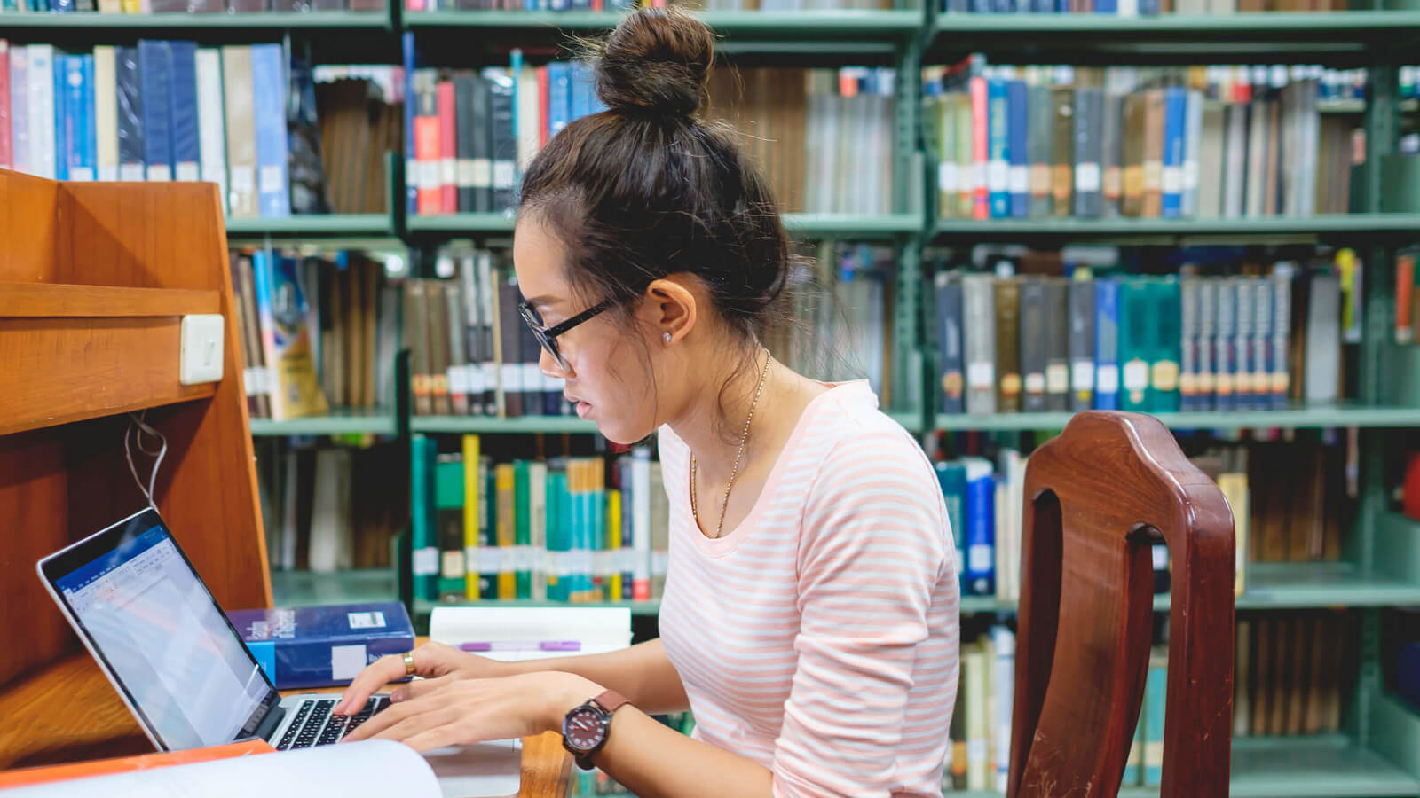 A woman studying with a laptop in a library