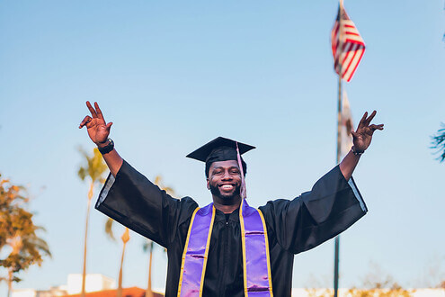 A college graduate raises his arms in celebration