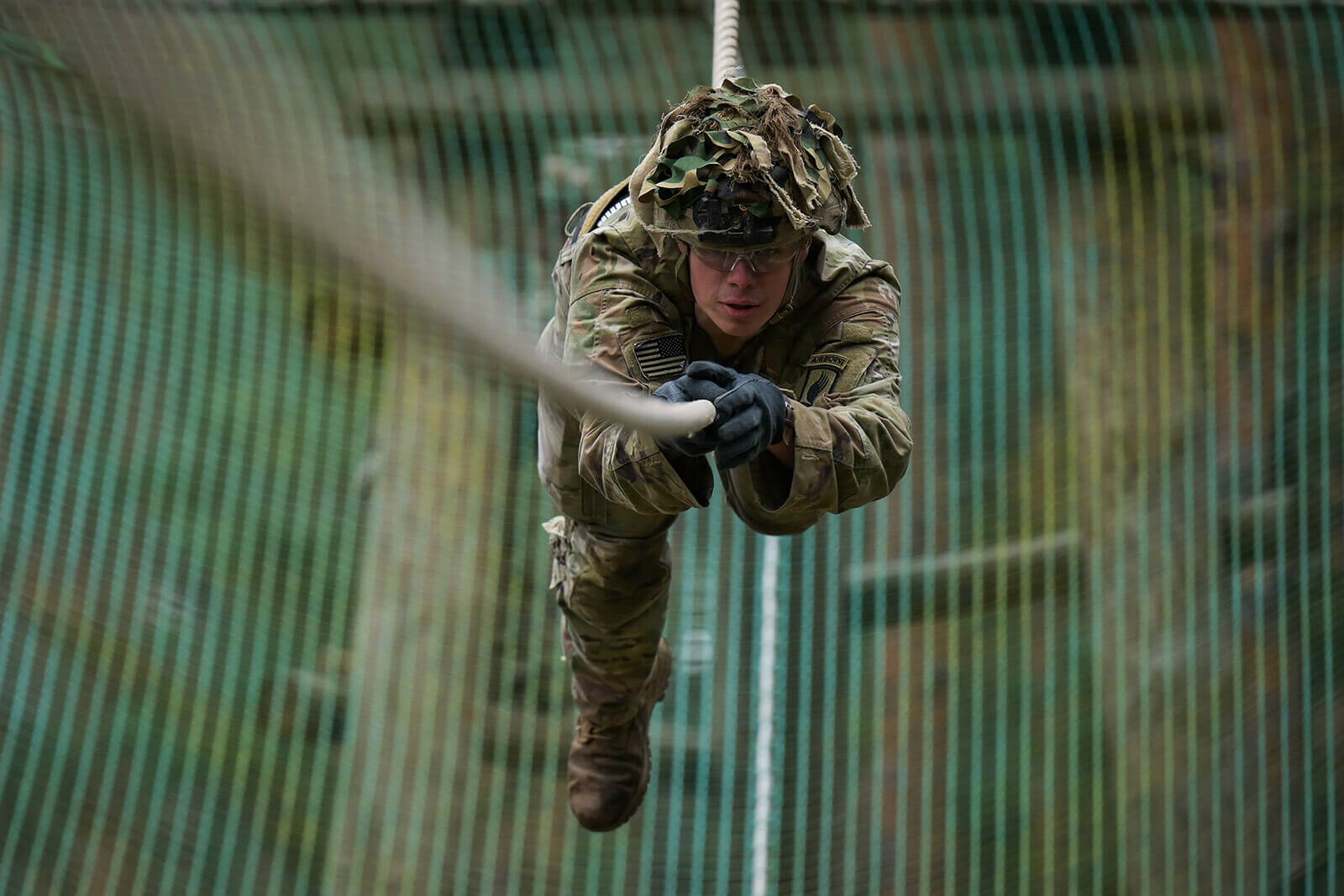 an army soldier rappels down a wall