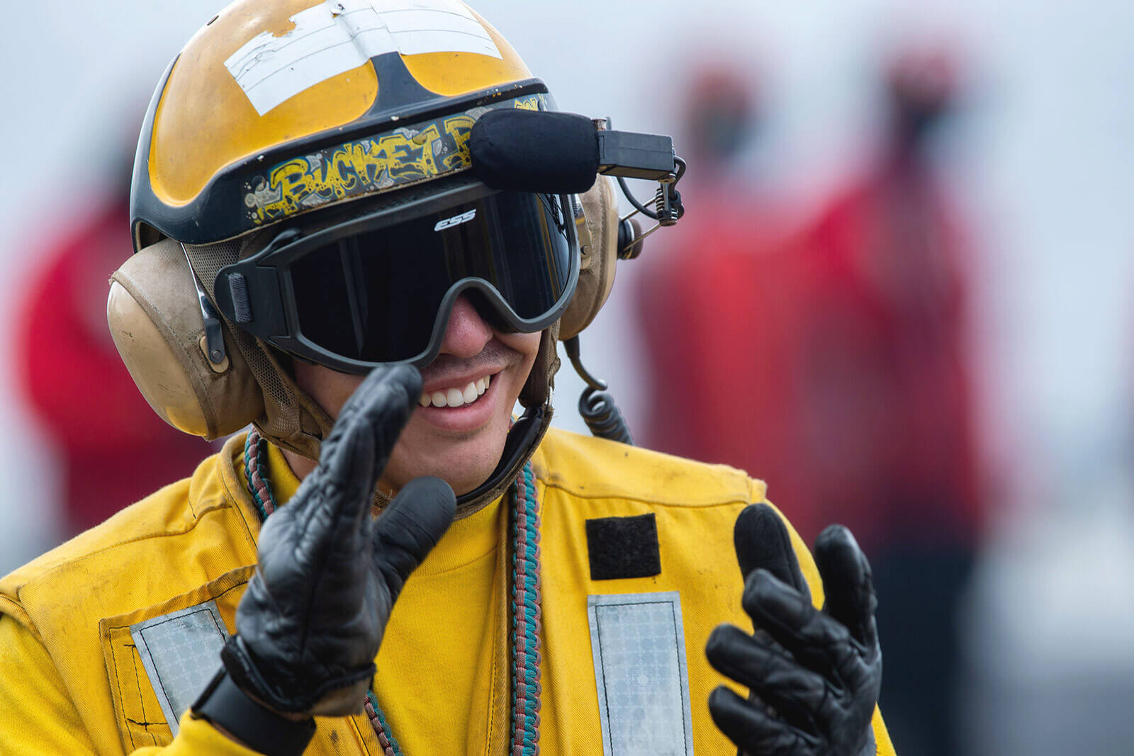 A Navy sailor claps his hands as a plane lands