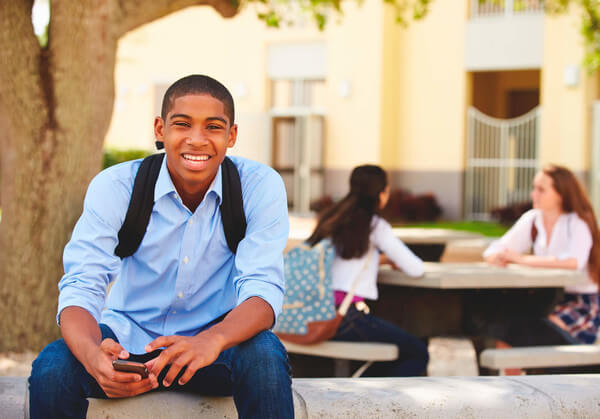 a male student smiles at the camera after hearing the news that he got merit aid