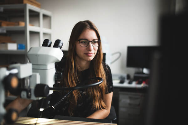 a student wearing glasses works in a lab at her high school