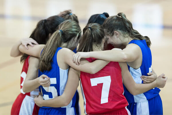 a group of girls in athletic uniforms huddle together