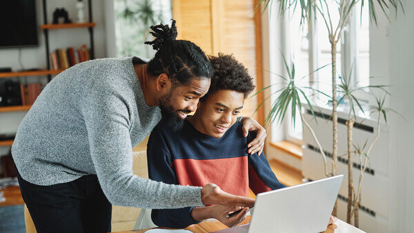A parent and son work together on a college application