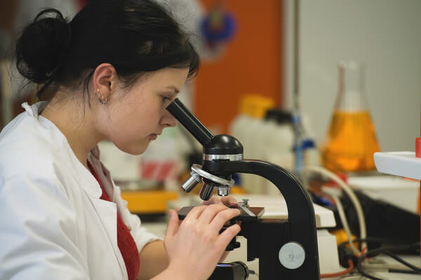 a student uses a microscope in her biology class