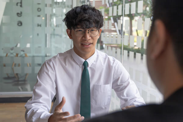 a student wears a white shirt and tie as he interviews with a college