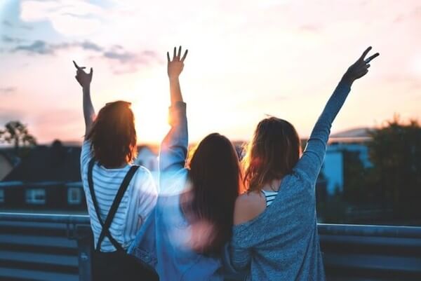 a group of college students with their arms in the air, shown from behind