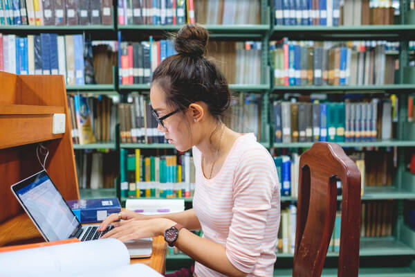 A woman studying with a laptop in a library