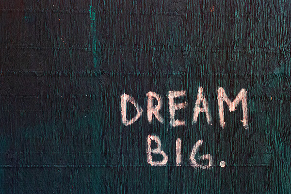 dream big written in pink chalk on a green wall
