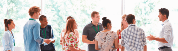 A counselor interacting with a group of students in a hall